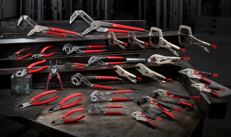 Assortment of Milwaukee hand tools displayed on a workbench, including pliers, clamps, wrenches, and locking tools, showcasing the durable, professional-grade options available at Spearfish Building Supply.
